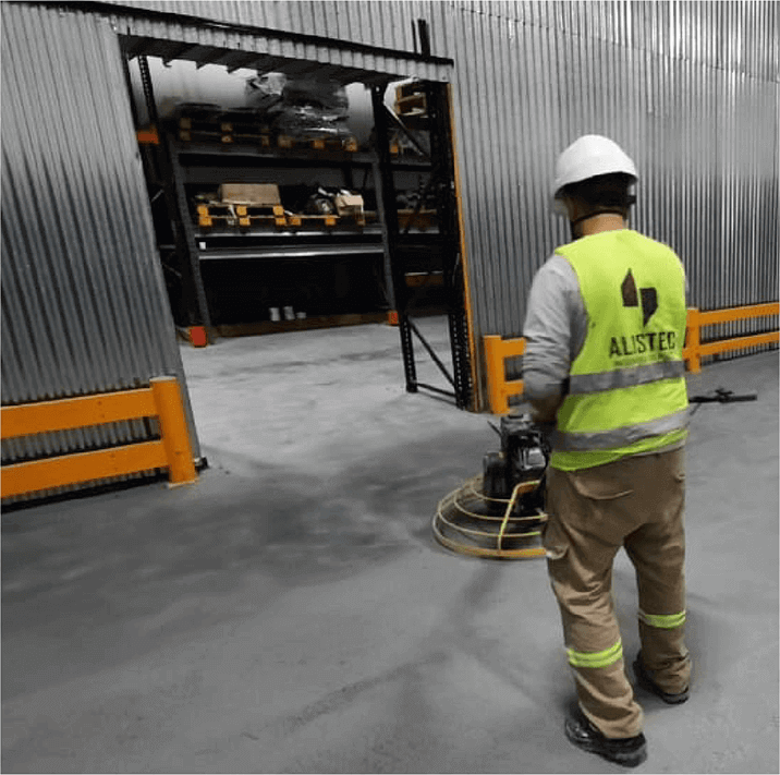 foto empleado de alistec de espaldas, puliendo el piso con una máquina